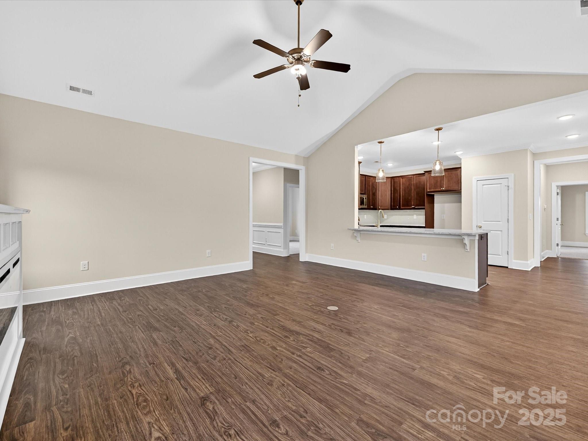 3030 Buffett Lane, Unit 49 Monroe, NC 28110 - Photo 6 of 27 an empty room with wooden floor a ceiling fan and kitchen view