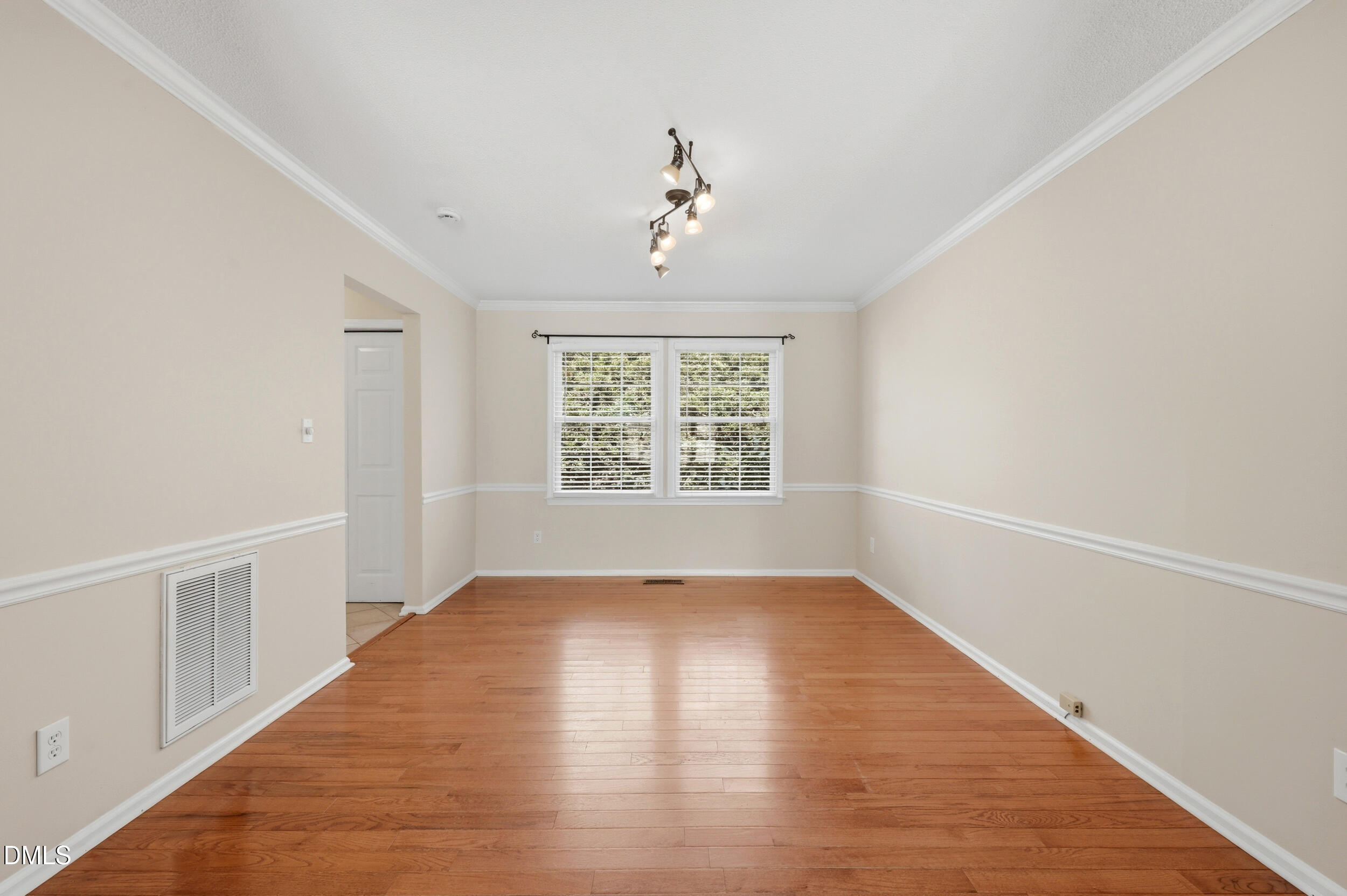 1713 Tealwood Place Raleigh, NC 27615 - Photo 6 of 26 an empty room with wooden floor chandelier and windows