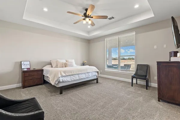 a bedroom with a bed a couch and a dresser with wooden floor