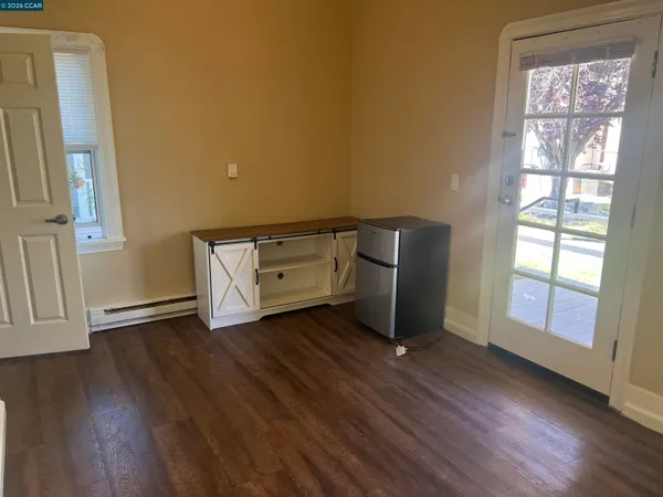 a view of an empty room with window and wooden floor