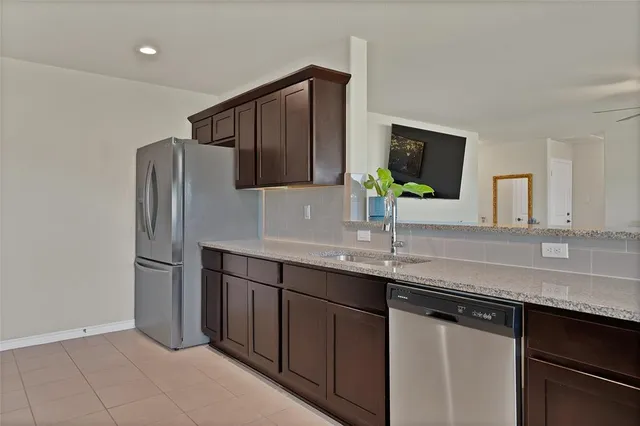 a kitchen with stainless steel appliances granite countertop a sink and a refrigerator