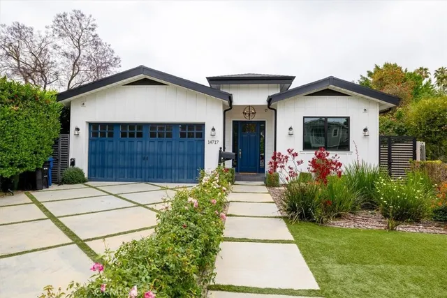 a front view of a house with a yard and potted plants
