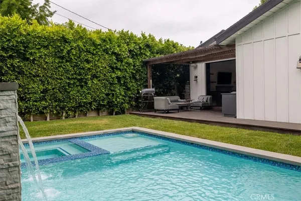 a view of swimming pool with lawn chairs and plants