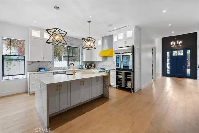 a large kitchen with stainless steel appliances granite countertop a sink a stove and a wooden floors