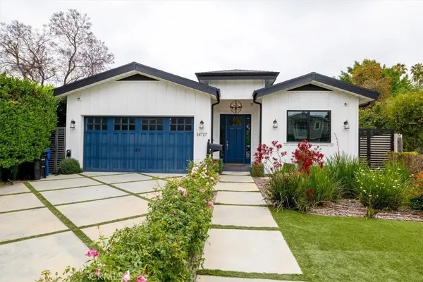 a front view of a house with a yard and potted plants
