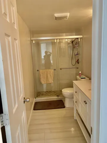 a bathroom with a granite countertop shower a toilet and a sink