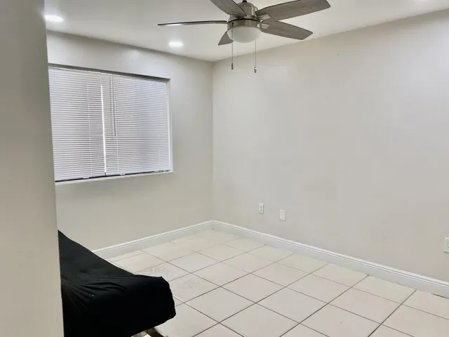 an empty room with a window and a fan