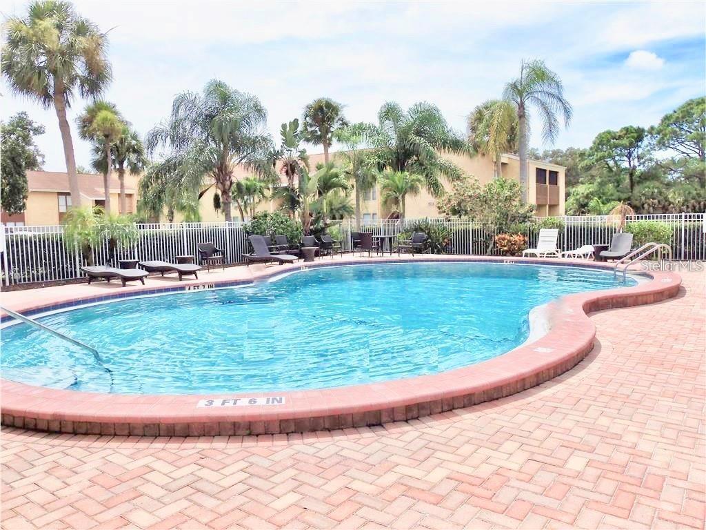 3405 Clark Road, Unit 106 Sarasota, FL 34231 - Photo 19 of 19 a view of a swimming pool and trees in the background