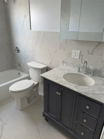 a bathroom with a granite countertop toilet sink and mirror