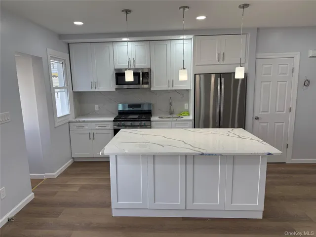 a kitchen with kitchen island granite countertop a stove a sink and a refrigerator