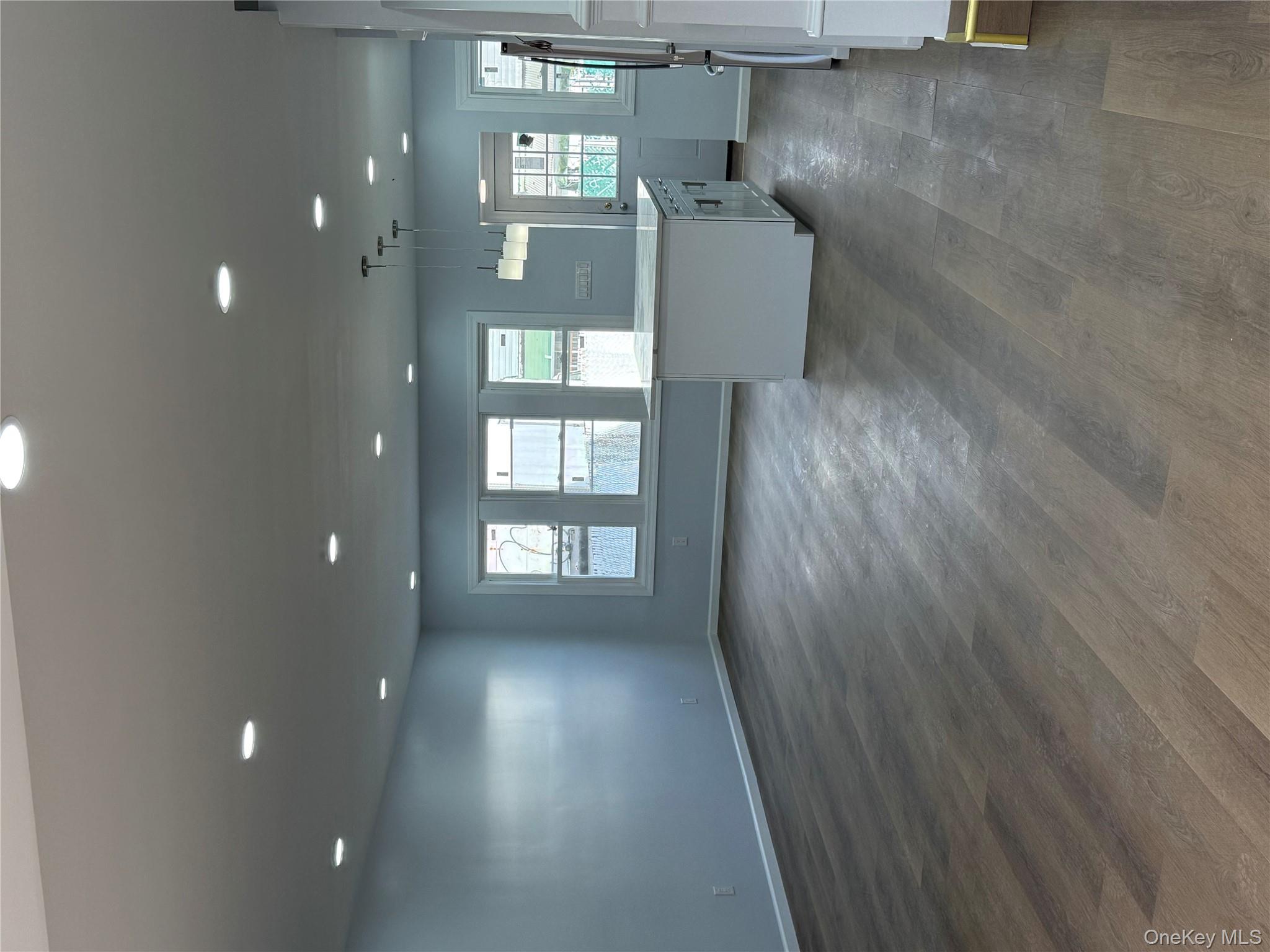 107-31 121st Street Queens, NY 11419 - Photo 6 of 20 an empty room with wooden floor and windows