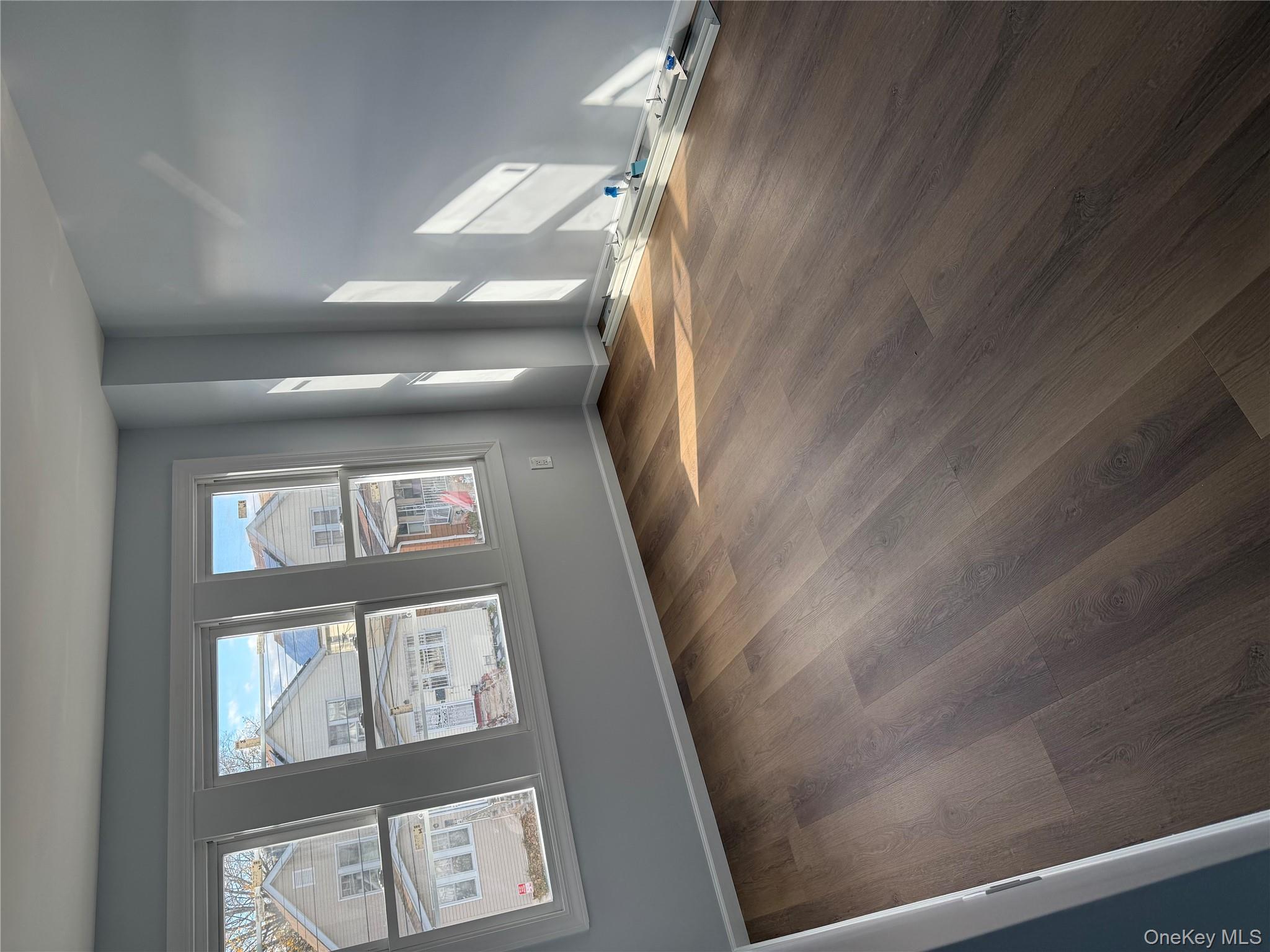 107-31 121st Street Queens, NY 11419 - Photo 7 of 20 an empty room with wooden floor and windows