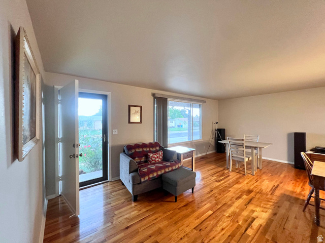 8097 South 535 East Sandy, UT 84070 - Photo 2 of 15 Hardwood flooring extends throughout this expansive living area, featuring a front entry door with a glass panel, a large window providing ample natural light, and neutral wall tones