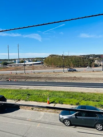 a view of a couple of cars parked on road with yard