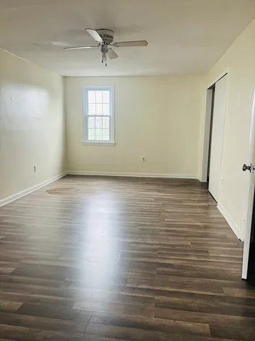 an empty room with wooden floor chandelier and windows