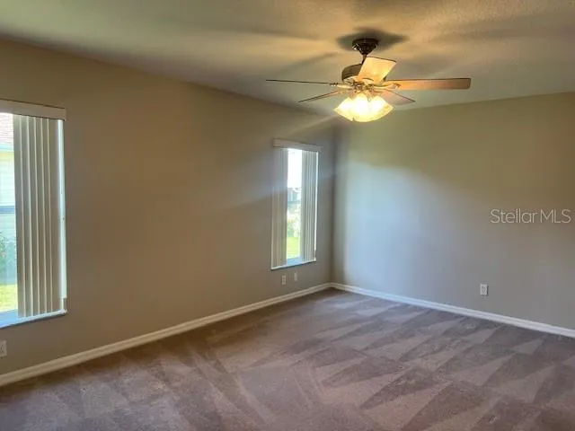 an empty room with a window and chandelier fan