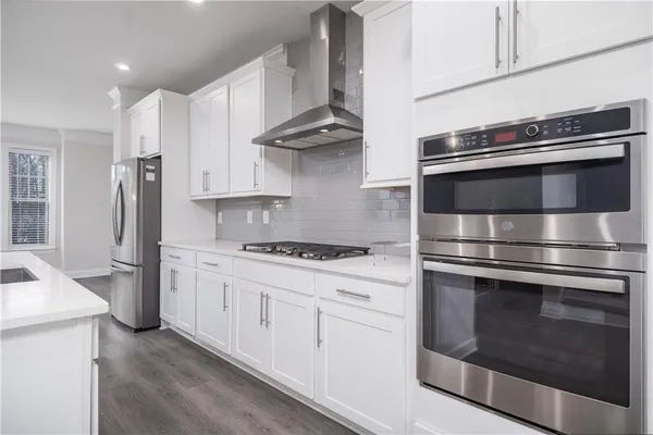 a kitchen with stainless steel appliances white cabinets and a stove top oven