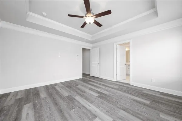 an empty room with wooden floor and ceiling fan