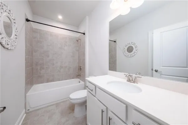 a bathroom with a bathtub shower sink vanity mirror and toilet