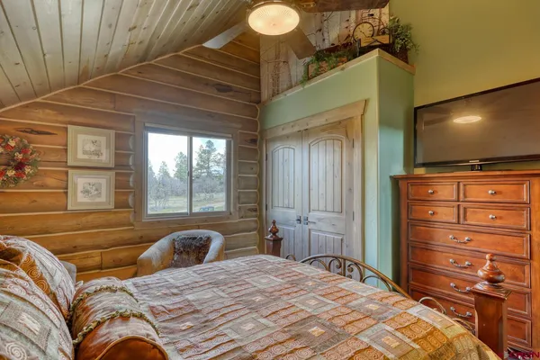 a bedroom with a bed and a flat tv screen on dresser