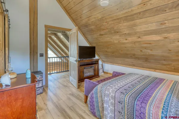 a bedroom with a bed a tv and wooden floor