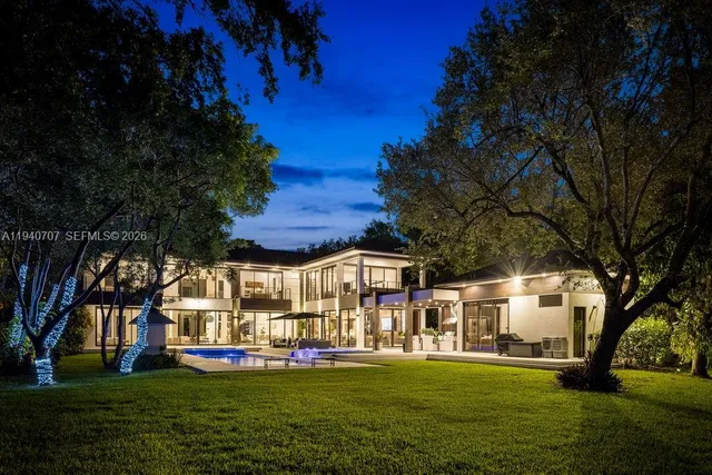 a view of a white house with a big yard and large trees