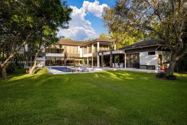 a view of a house with a big yard patio and large trees