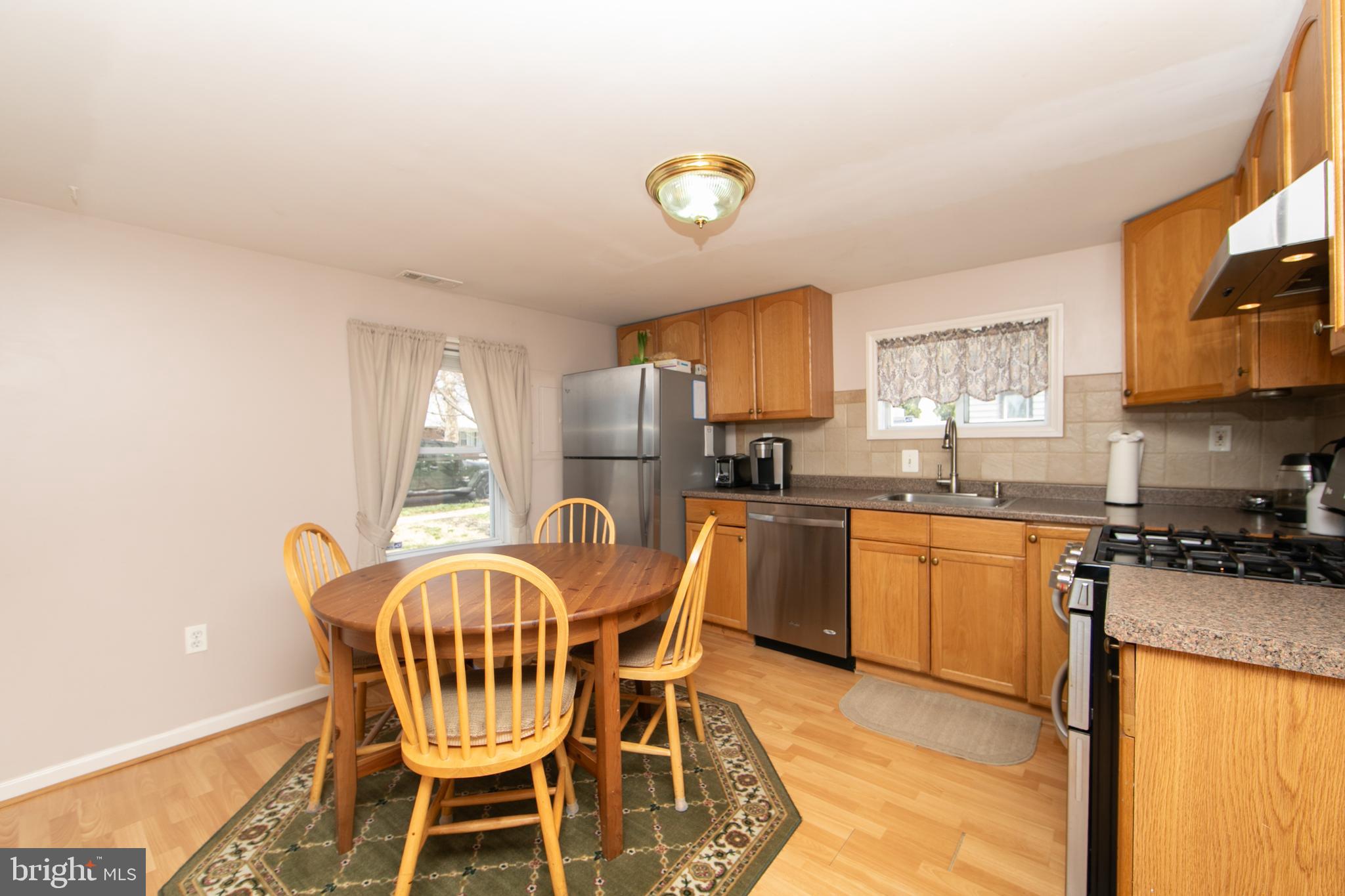 614 West 5th Street Palmyra, NJ 08065 - Photo 10 of 30 a kitchen with granite countertop a dining table chairs a refrigerator a stove a sink and dishwasher with wooden floor