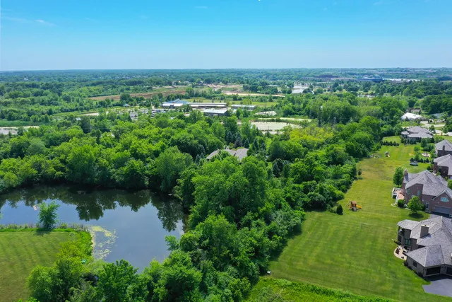 an aerial view of a houses with a yard and lake view