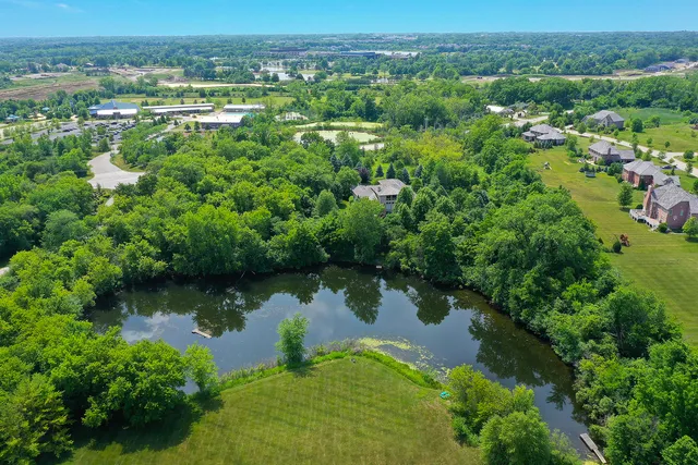 an aerial view of lake residential house with outdoor space and trees all around