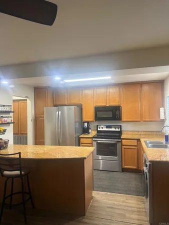 a kitchen with stainless steel appliances kitchen island granite countertop a stove a sink and a refrigerator
