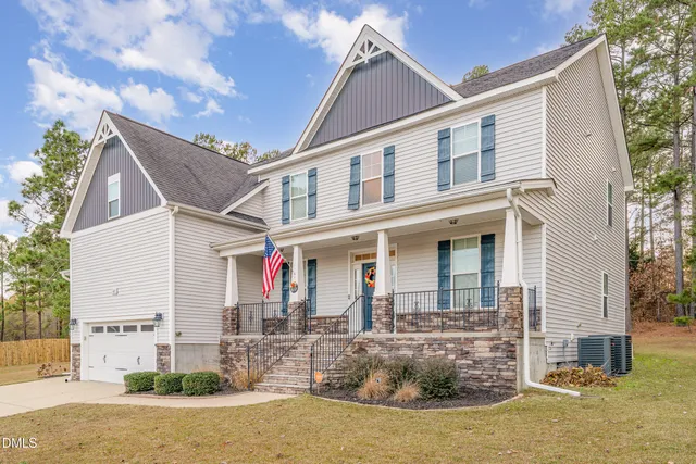 a view of a white house with a small yard and a large tree