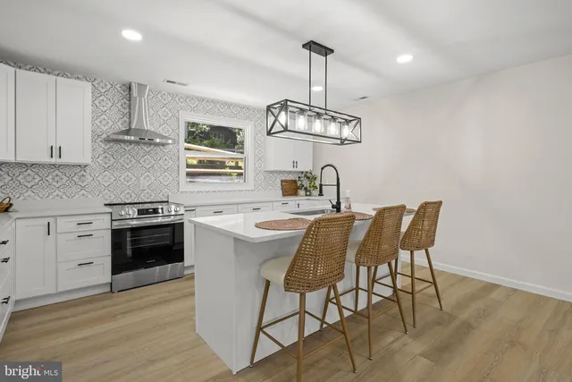 a kitchen with stainless steel appliances a kitchen island hardwood floor sink stove dining table and chairs