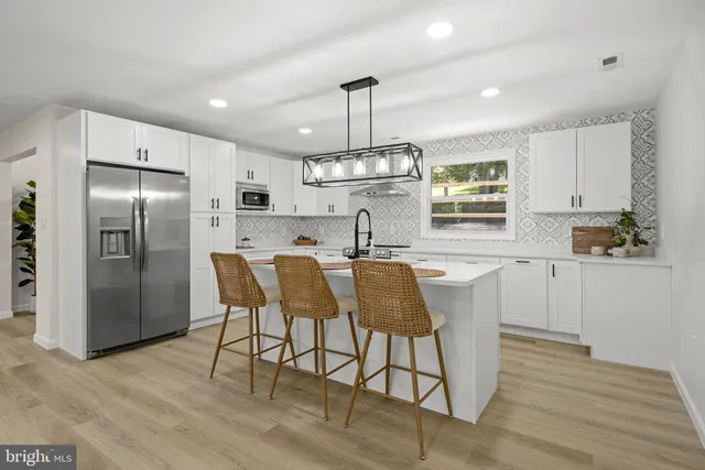 a kitchen with stainless steel appliances granite countertop a dining table chairs refrigerator and cabinets