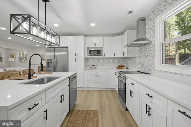 a kitchen with kitchen island white cabinets appliances and a large window