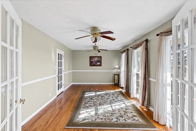 a view of a hallway to a livingroom with wooden floor and a ceiling fan