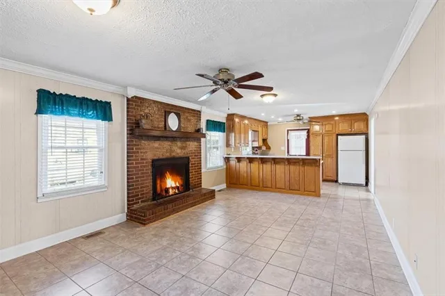 a view of a livingroom with a fireplace a ceiling fan and windows