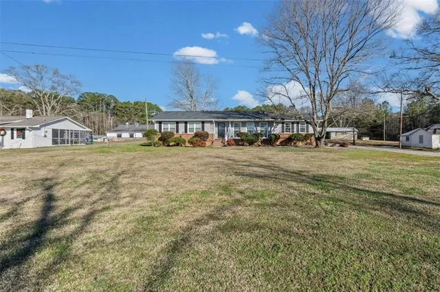 a view of a big house with a big yard and large trees