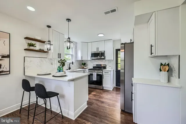 a kitchen with kitchen island white cabinets and stainless steel appliances