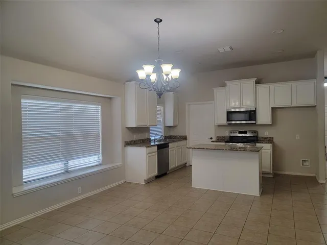 a kitchen with stainless steel appliances granite countertop a stove top oven a sink dishwasher and a refrigerator with wooden floor