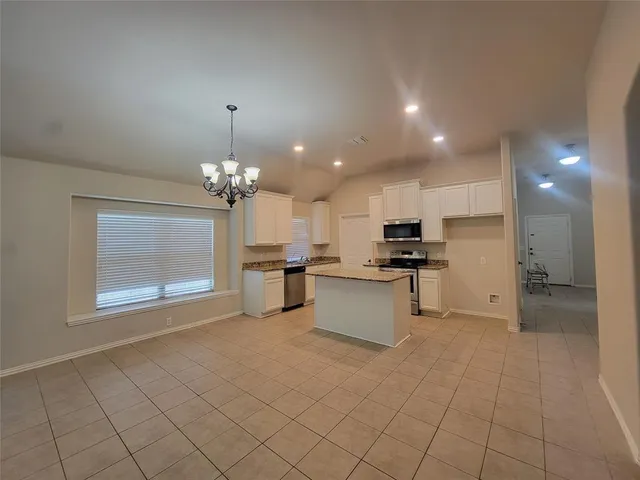 a view of kitchen with kitchen island granite countertop a stove top oven a sink a counter top space and cabinets