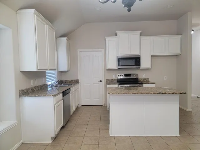 a kitchen with stainless steel appliances granite countertop a stove top oven a sink a microwave and wooden cabinets