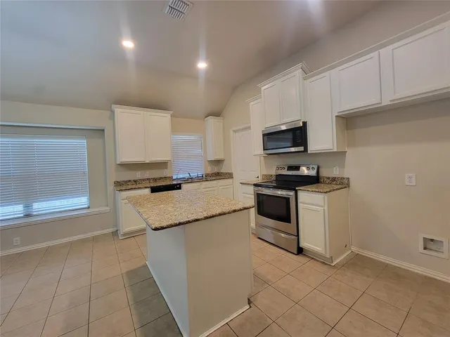 a kitchen with granite countertop a stove top oven and cabinets