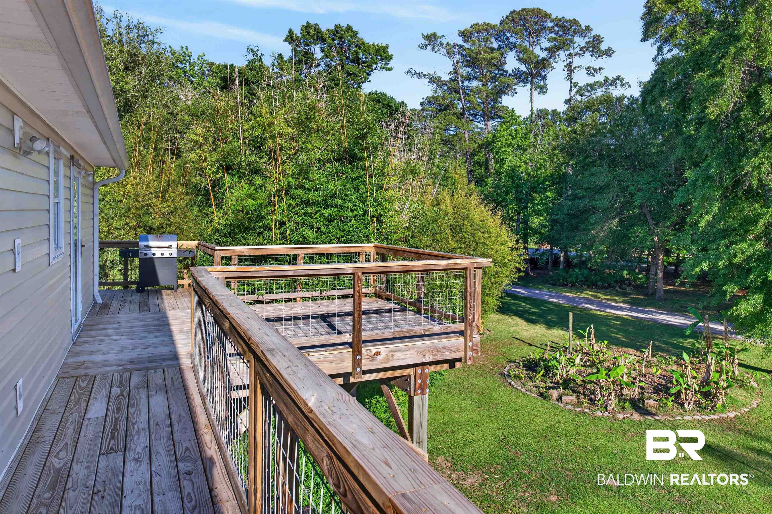 9624 North Bay Street Foley, AL 36535 - Photo 47 of 59 Expansive wood-finish deck featuring metal wire railings, a secondary elevated deck section, and direct access to the interior