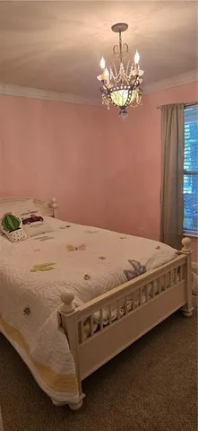 a bed sitting in a spacious bedroom next to a chandelier