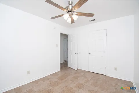 an empty room with a chandelier fan and windows