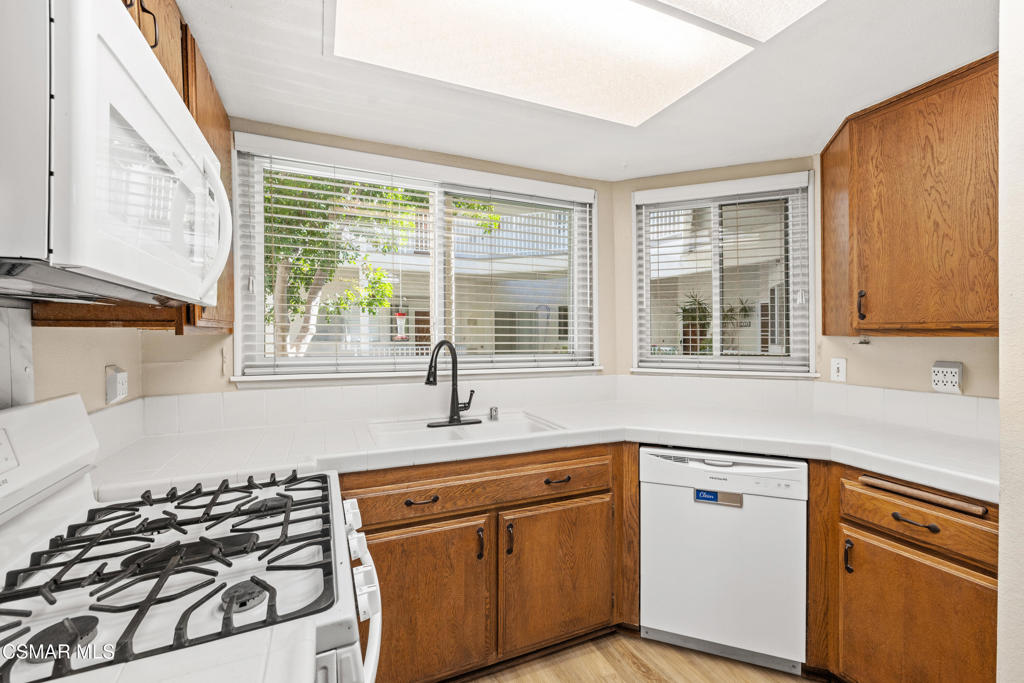 3354 Darby Street, Unit 313 Simi Valley, CA 93063 - Photo 12 of 30 a kitchen with stainless steel appliances granite countertop a sink a stove and a granite counter tops with a window
