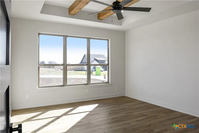 an empty room with wooden floor fan and windows