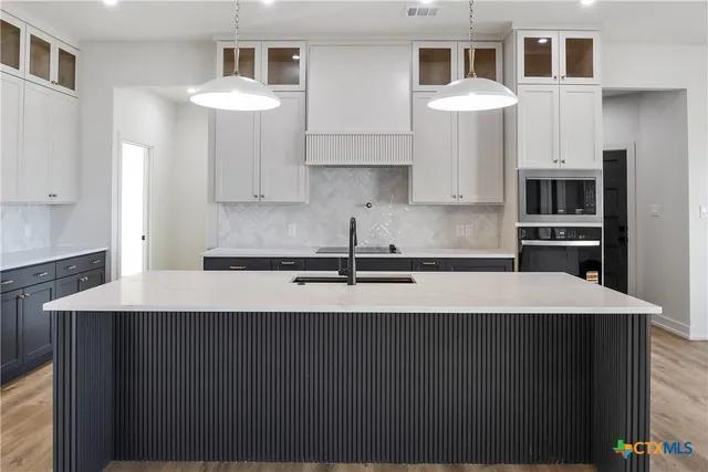 a kitchen with stainless steel appliances a sink dishwasher a refrigerator white cabinets and wooden floor