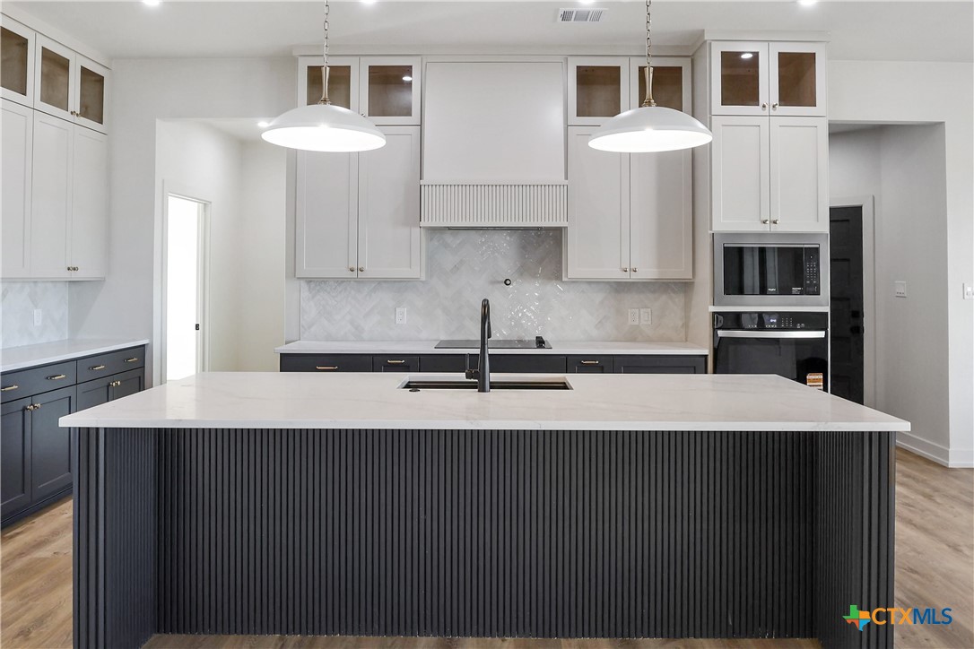 16026 Honey Ridge Drive Holland, TX 76534 - Photo 4 of 27 a kitchen with stainless steel appliances a sink dishwasher a refrigerator white cabinets and wooden floor